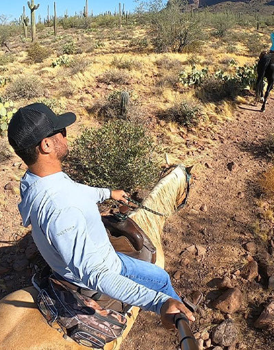 Andy Gonzales of Anetik wearing performance long sleeve shirt horseback riding through a desert landscape with cacti