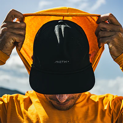 Man pulling up a hood over a cap while wearing sun-protective performance clothing